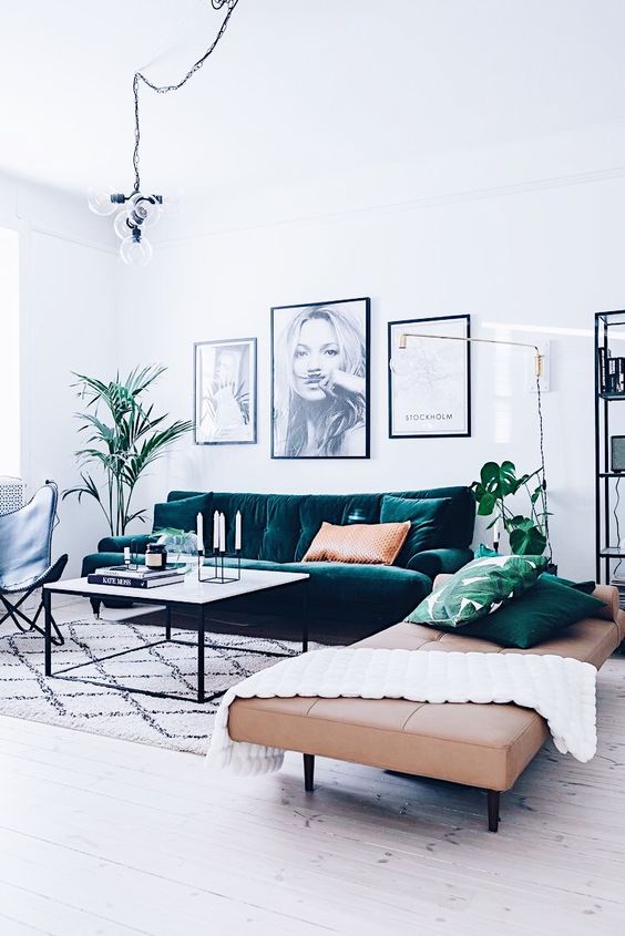 a serene Scandinavian living room with a dark green sofa, a beige leather daybed, a blakc leather chair, a coffee table and a black and white mini gallery wall