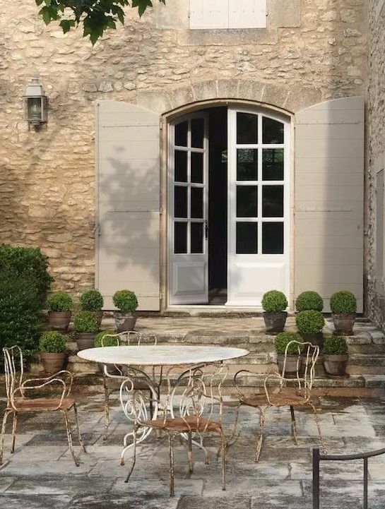 a shabby chic Provence terrace with a round metal table and chairs, potted greenery and lanterns is a lovely idea for a French farmhouse