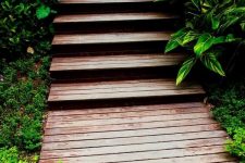 a simple stained planked wooden walkway with steps is a classic idea for any garden, from a modern to a zen-like one