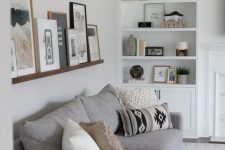 a stained ledge over the couch shows off black and white and colorful art in stained wood and black frames