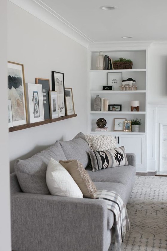 a stained ledge over the couch shows off black and white and colorful art in stained wood and black frames