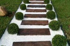 a stained wood garden path with white gravel and boxwood looks very formal, elegant and inviting thanks to the contrast created