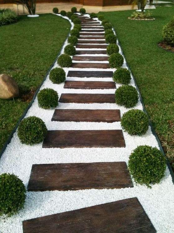 a stained wood garden path with white gravel and boxwood looks very formal, elegant and inviting thanks to the contrast created