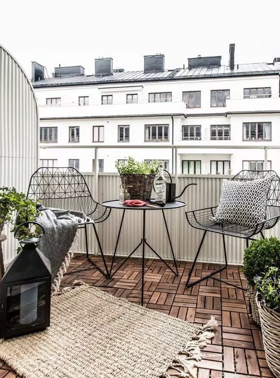 a stylish Scandinavian balcony with black metal chairs and a coffee table, candle lanterns and potted plants is a very stylish idea for a Nrodic style lover