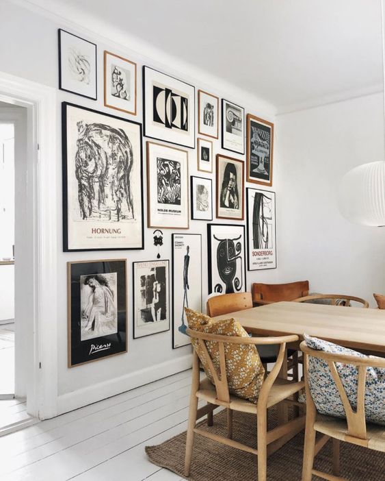 a stylish Scandinavian dining room with a light-stained table and matching chairs, a statement black and white gallery wall
