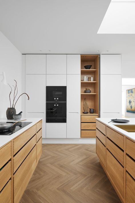 a stylish kitchen with no hardware cabinets, light stained and white ones, built in appliances and a skylight to give more natural light to the space