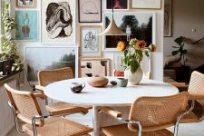 a stylish mid-century modern dining room with a round stone table, cane chairs, a lovely gallery wall and a pendant lamp