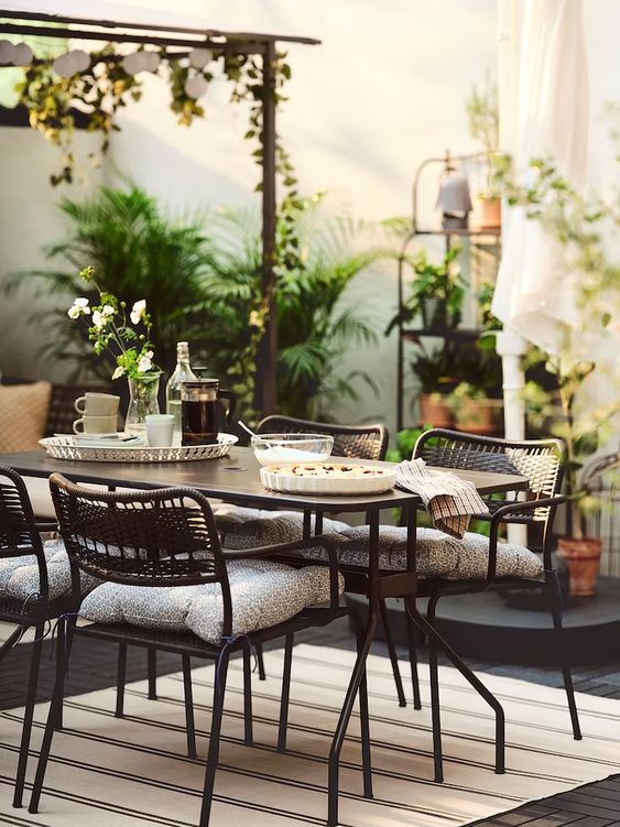 a stylish modern deck with a black metal dining set and lots of greenery around is a lovely space for having meals
