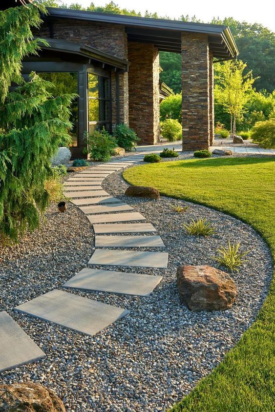 a stylish modern garden with green lawn, rocks, moss, trees and a curved gravel pathway with additional stone steps