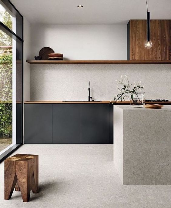 a super chic minimalist kitchen with no hardware cabinets, a wood slab kitchen island, wood slat cabients and a wooden stool