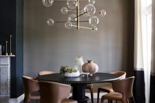 a taupe dining space wiht a large round table in black, rust-colored leather chairs and a catchy bubble chandelier
