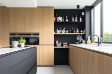 a two-tone kitchen with sleek light-stained cabinets, a black kitchen island and black open shelves in the corner