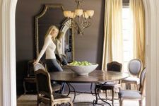 a vintage-inspired taupe dining room with a round table, vintage neutral chairs, a chandelier and a large mirror