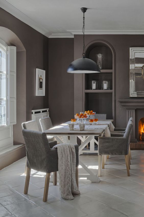 a vintage-inspired taupe dining room with a window in an alcove, built-in shelves, a fireplace, a trestle dining table and grey chairs