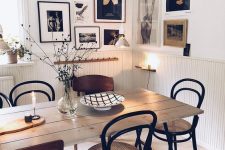 a welcoming Scandinavian dining space with creamy paneling, a planked table and vintage chairs, a chic corner gallery wall