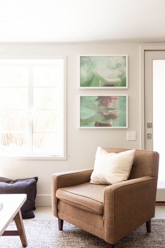 a welcoming neutral living room with light grey walls, a brown chair, a mini gallery wall with personal photos