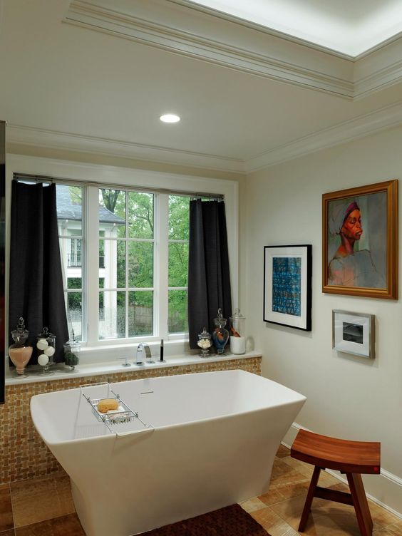 a whimsical bathroom with a uniquely shaped bathtub, a mini gallery wall and a wooden stool to make the space cooler