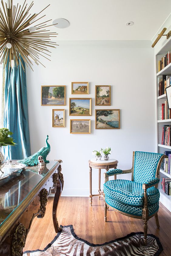 a whimsical vintage home office with a refined desk, a turquoise chair, a lovely side table, a large storage unit and a vintage gallery wall