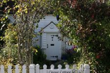 a white picket fence with an entrance arch of bushes and blooming plants is a beautiful idea for a cozy cottage