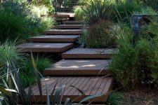 a wooden walkway placed of wooden pallet-like tiles is a lovely idea for a modern or contemporary garden and adds a warm feel to the space