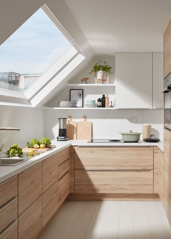 an attic U-shaped kitchen with no hardware light-stained cabinets and white ones, a skylight and built-in appliances