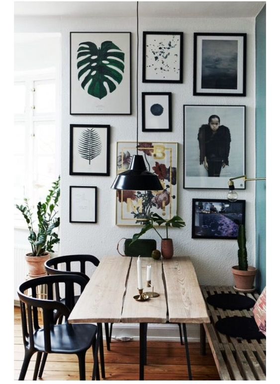 an eclectic dining room with a planked table, a pallet bench and black chairs plus a lovely free form gallery wall