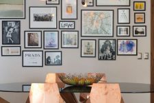 an elegant dining room with a glass table, copper faceted chairs, a chic chandelier and a free form gallery wall