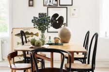 an elegant mid-century modern dining room with a stained table and mismatching chairs, a chic free form gallery wall and some decor