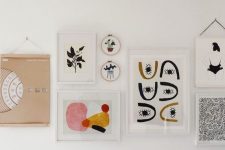 an eye-catchy gallery wall with white and blonde wood frames, with bold graphic artworks is chic and cool