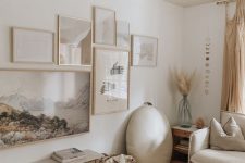 en ethereal free form gallery wall with thin blonde wood frames and pale and muted color artworks looks very cohesive