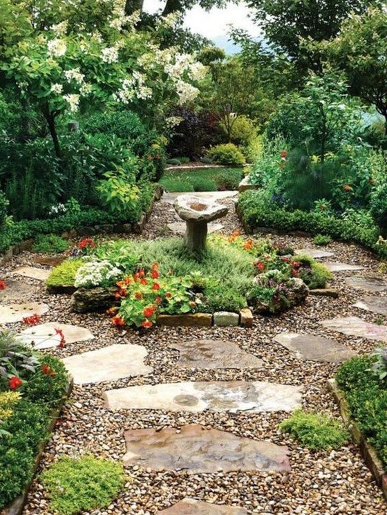 gravel paths combined with rocks, a stone fountain, greenery and blooms create a look of a wild garden