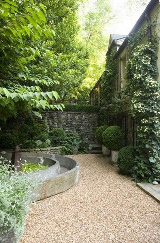 neutral-colored gravel combined with concrete and stone plus lush potted greeenery for a modern garden