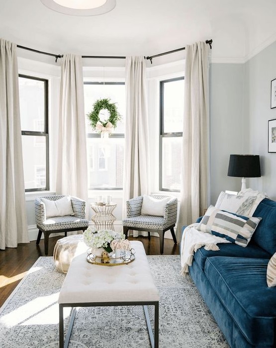 a bay window with several neutral curtains that add coziness and chic to the space and block out excessive sunshine