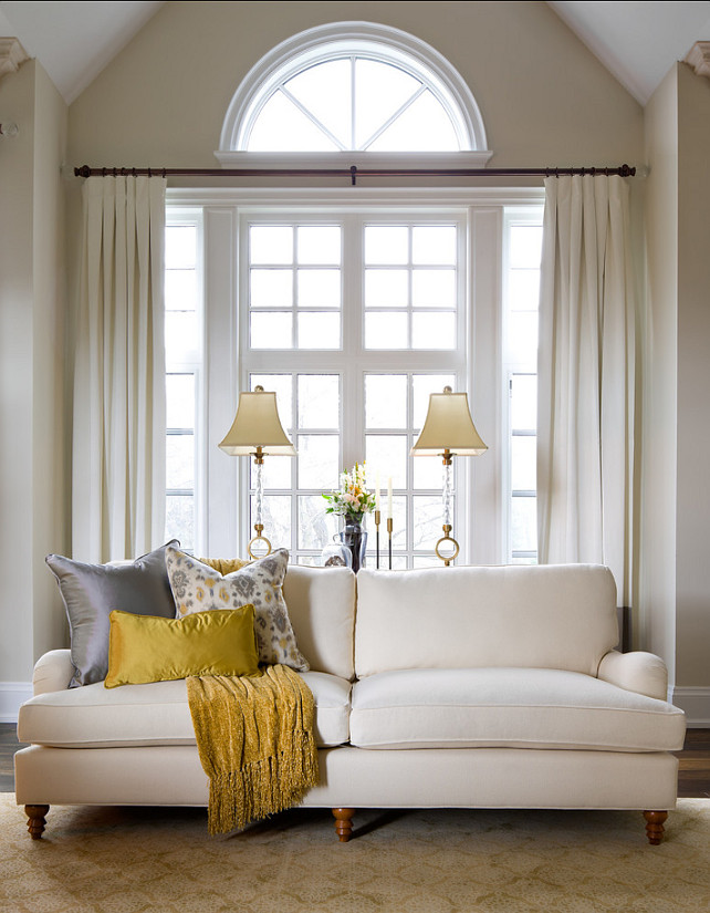 a large window with a half circle piece done with creamy drapes and the piece above stays uncovered - a stylish and cool solution