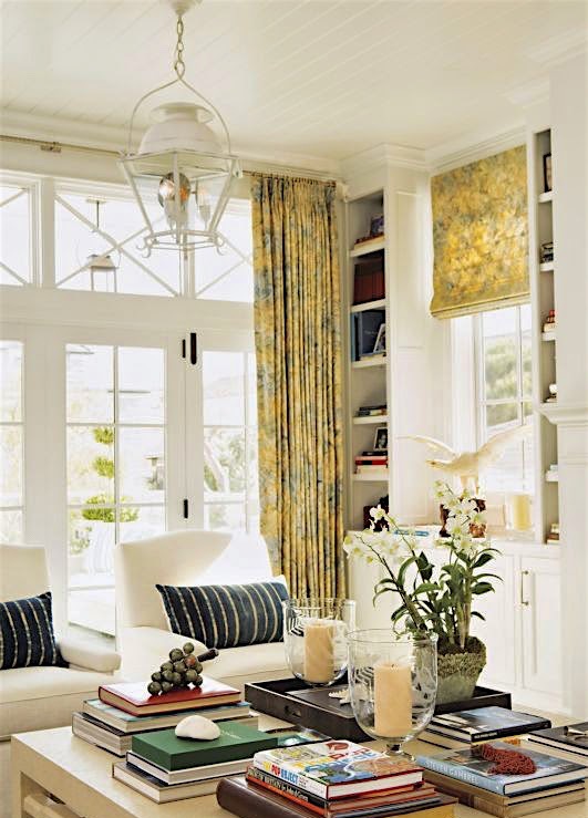 a modern and refined living room featuring a glazed wall with French windows and doors, clerestory windows, printed yellow curtains and blinds