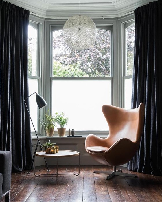 a bay window covered with elegant black velvet draperies to make it more private and block out the sun