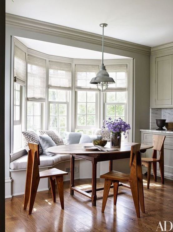 a cozy farmhouse dining space with a bow window featuring semi sheer blinds on each part to make the space more private when needed