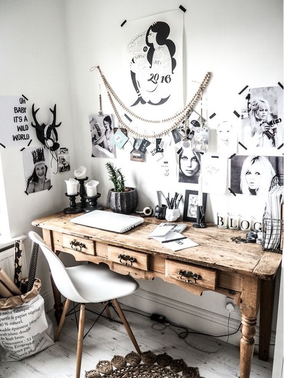 a Nordic home office with a wooden vintage desk, a white chair and a black and white gallery wall with no frames