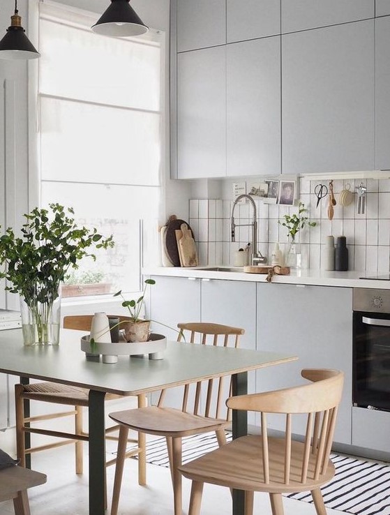 a Nordic kitchen in dove grey, with a white stacked tile backsplash, touches of black and wooden chairs