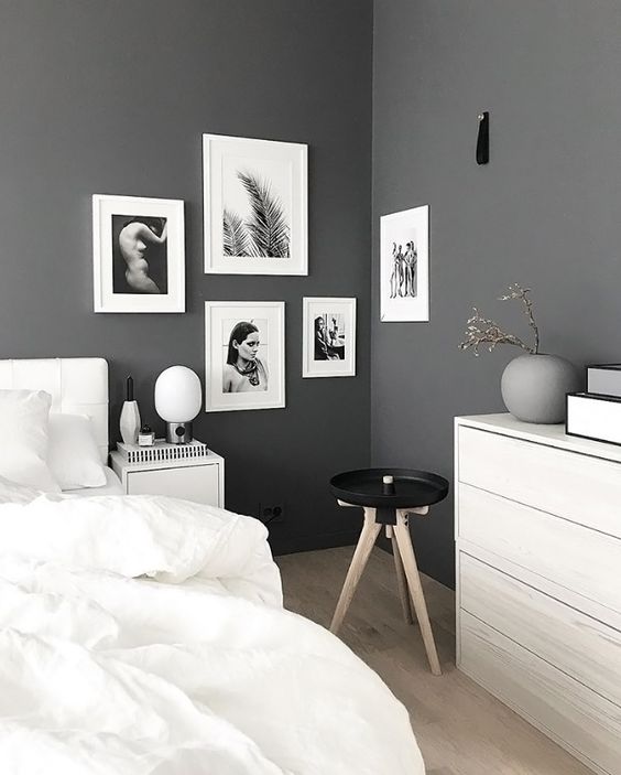 a Scandinavian bedroom with grey walls, white furniture, white bedding, a catchy black and white gallery wall in the corner