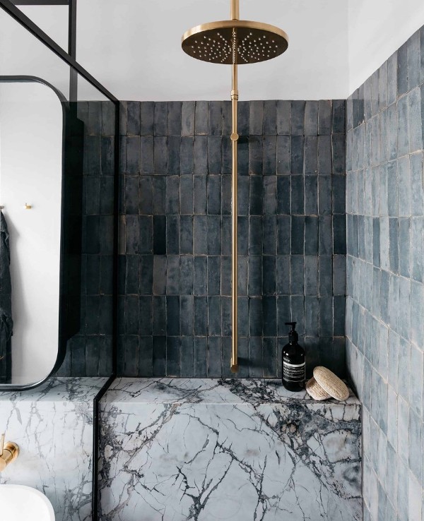 a bathroom with grey skinny Zellige tiles stacked, white marble and brass fixtures is an amazing contemporary space
