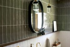 a beautiful and elegant bathroom with green and white stacked tiles, a dark-stained vanity with a sink, an oval mirror and pendant lamps