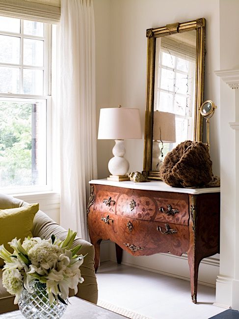 a beautiful ornate stained sideboard with a white stone countertop, a large mirror and a chic table lamp are a great combo for a living room