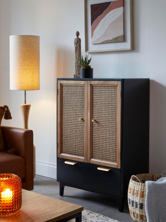 a black cabinet with a large drawer and cane webbing doors is an elegant and timeless solution for a boho or mid-century modern space and it looks very contrasting