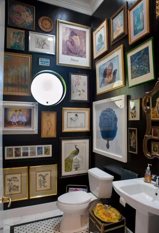 a black powder room with a round window, vintage artwork all over the space, white appliances and lights here and there