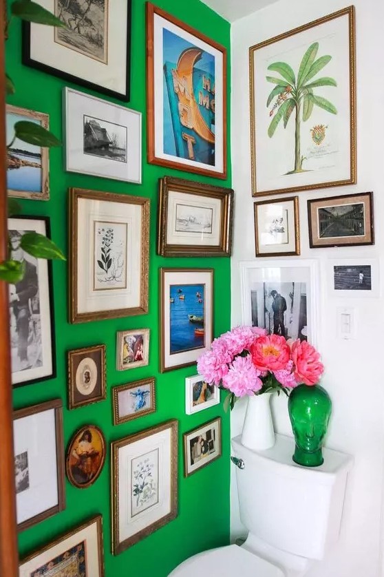 a bold and catchy bathroom with a green accent wall, a colorful gallery wall, white appliances and bold blooms