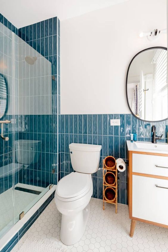 a catchy modern bathroom with bold blue stacked tiles, white hex tiles on the floor, a neutral vanity and white appliances