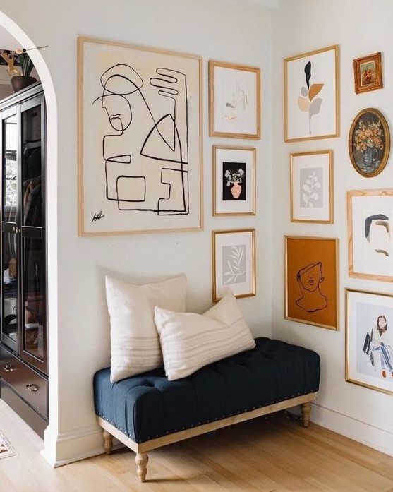 a chic gallery wall with gold and blonde wood frames and abstract art of various kinds