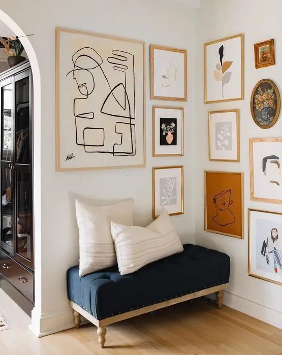 a chic gallery wall with mismatching wood and gold frames and various abstract art to accent a little nook