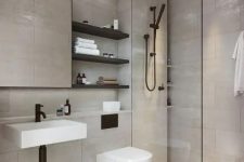 a clean contemporary bathroom clad with neutral tiles, a shower space, a mirror, black shelves and black fixtures
